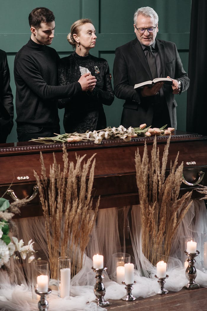A heartfelt funeral ceremony with family gathered around a coffin adorned with flowers and lit candles.